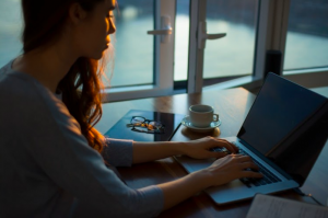 A woman typing on a laptop while sitting at a table