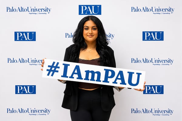 Shirin Aghakhani poses in front of a Palo Alto University backdrop holding an 